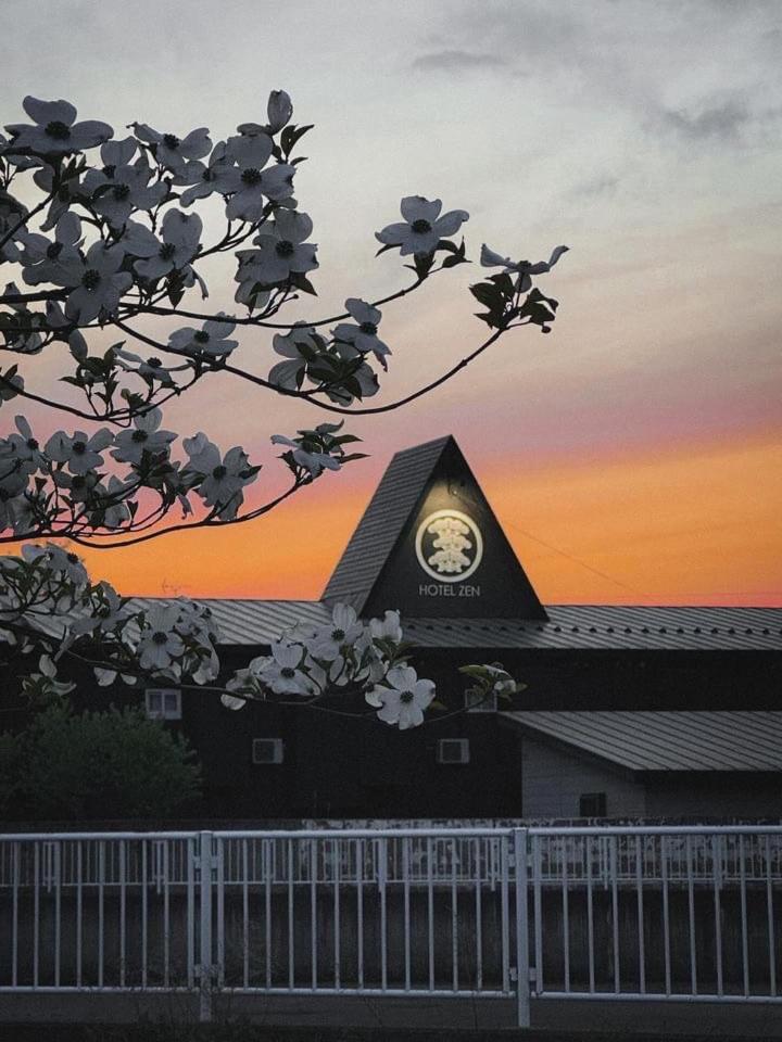 une horloge au sommet d'un bâtiment avec un arbre dans l'établissement HOTEL ZEN-Adult Only, à Hirosaki