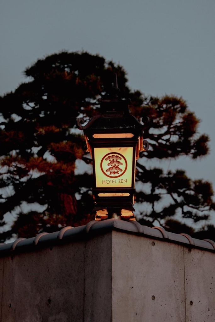 une lumière au sommet d'un mur avec un arbre en arrière-plan dans l'établissement HOTEL ZEN-Adult Only, à Hirosaki