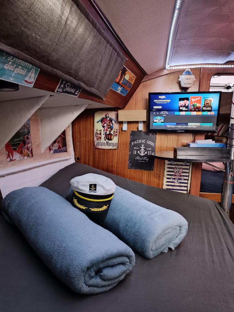 Cette chambre dispose d'une télévision et d'un fauteuil avec des poufs bleus. dans l'établissement Le Nid Marin,Un Voilier Pour Deux Sète Vieux Port, à Sète