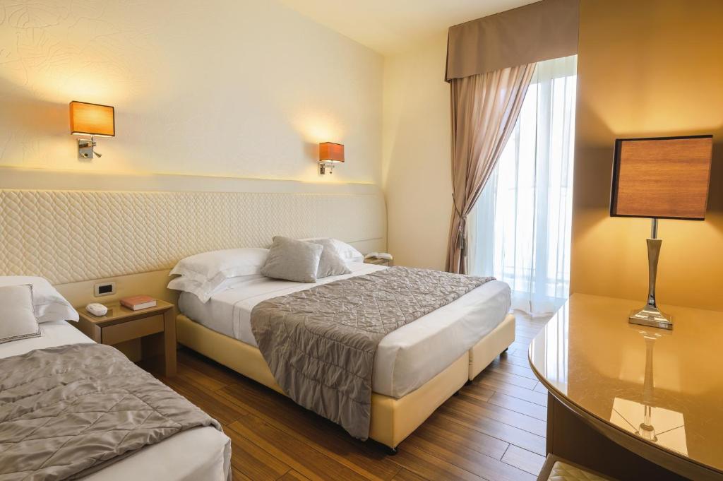 une chambre d'hôtel avec deux lits et une fenêtre dans l'établissement Hotel Alexander, à Milano Marittima