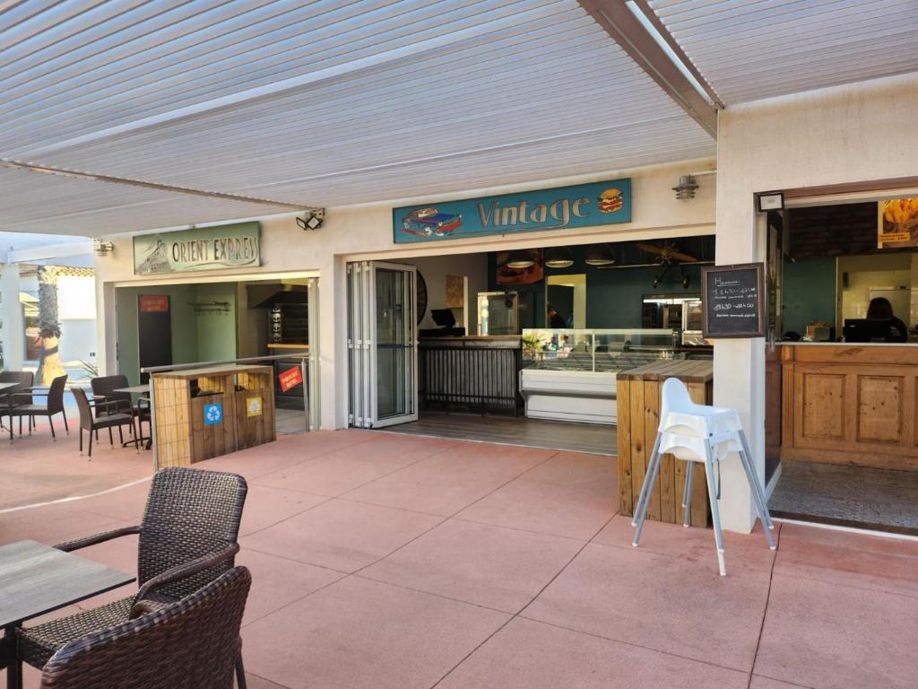 un restaurant avec des chaises, des tables et un comptoir dans l'établissement MOBILHOME Lodge 3 chambres, 500m plage, camp 5 étoiles, à Vendres