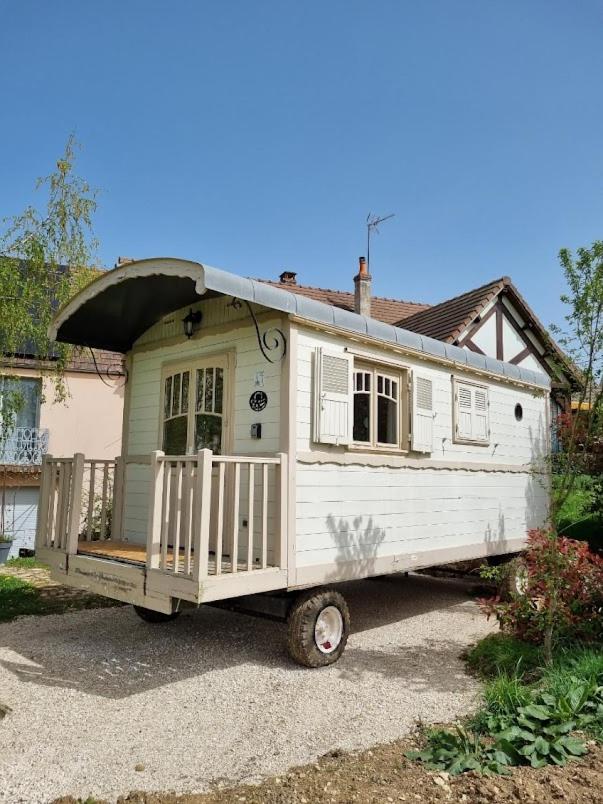 une petite maison blanche garée devant une maison dans l'établissement Villa Rose La Belle Roulotte, à Escolives-Sainte-Camille
