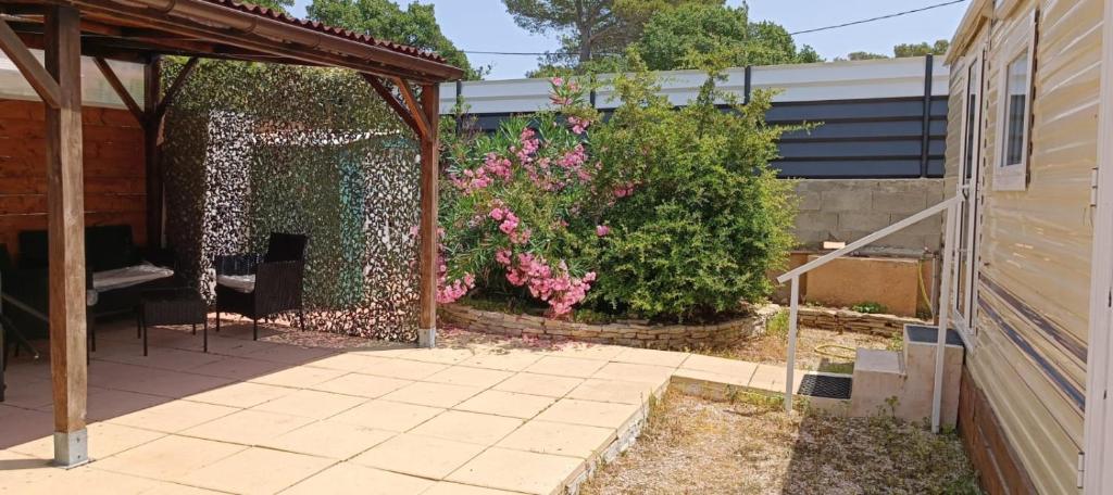 un patio avec une clôture et un buisson à fleurs roses dans l'établissement Havre de paix pour 2 à 4 pers., au Castellet
