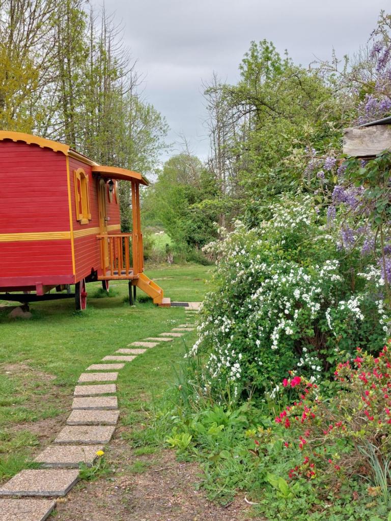 un jardin avec une maison et un chemin de jardin dans l'établissement Roulotte ZEN, à La Saunière