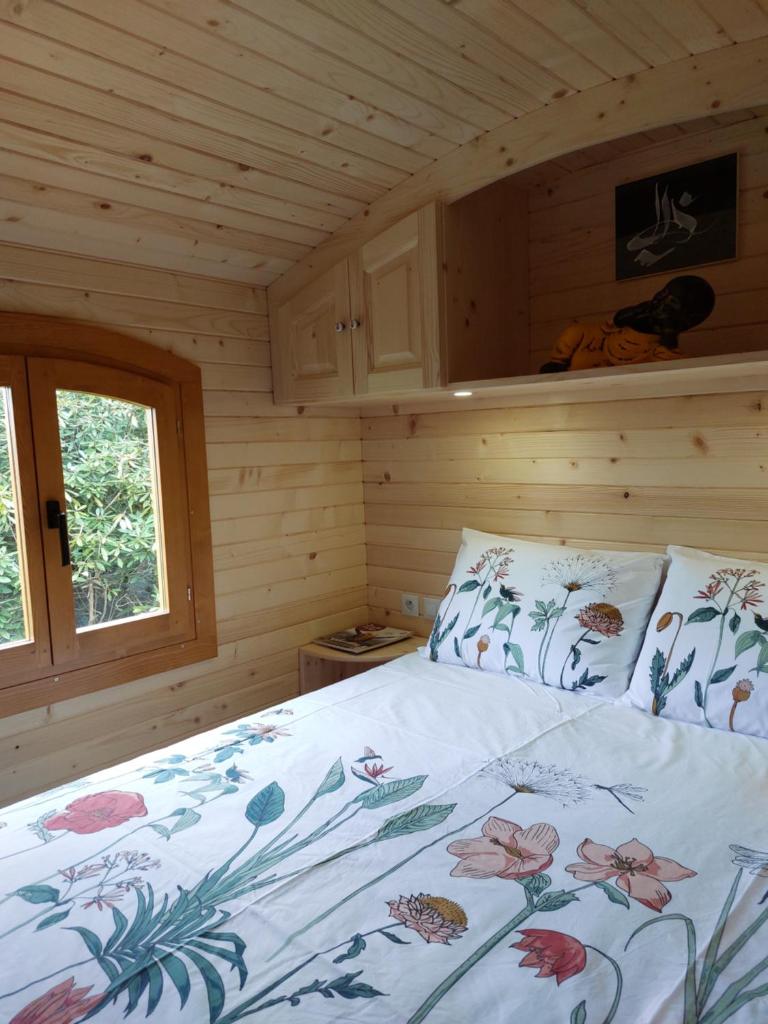 une chambre avec un lit dans une cabane en bois dans l'établissement Roulotte ZEN, à La Saunière