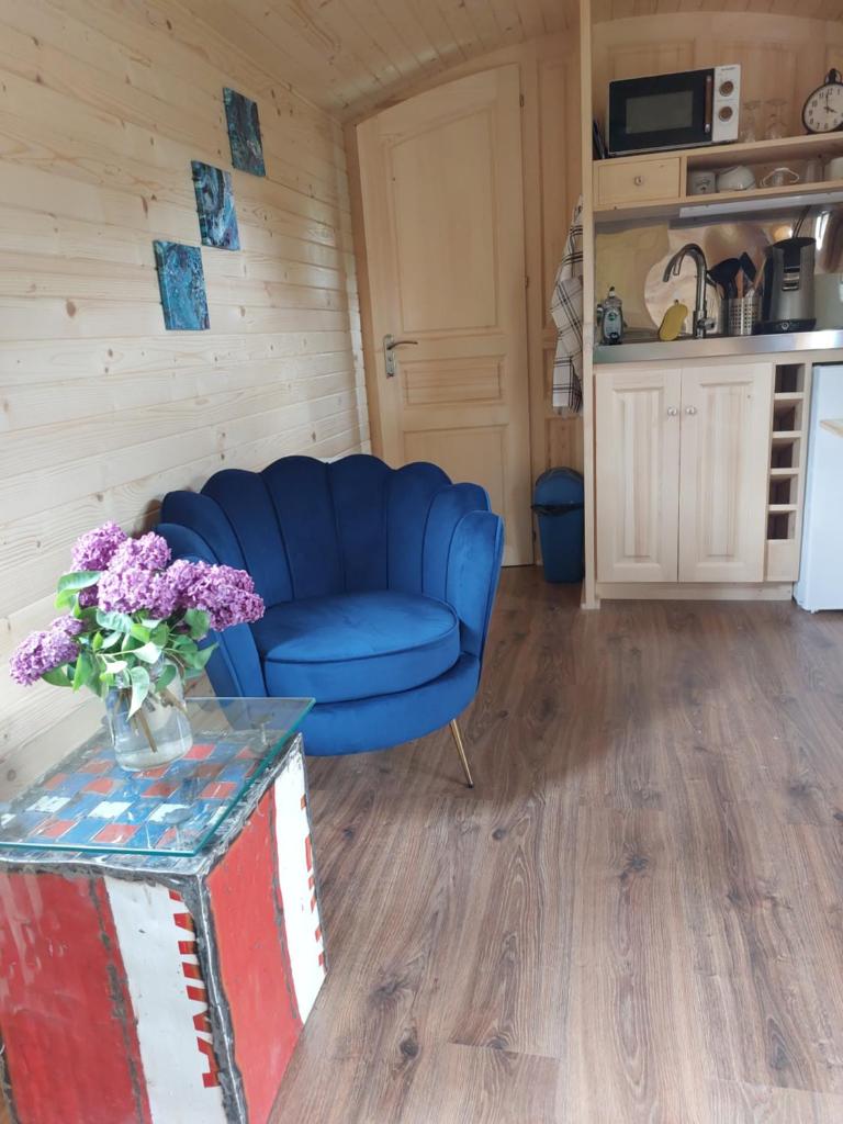 un salon avec un canapé bleu et une table dans l'établissement Roulotte ZEN, à La Saunière