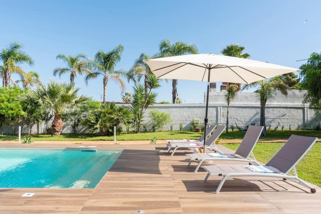 - un groupe de chaises et un parasol à côté de la piscine dans l'établissement Le Perseidi Eco Home San Lorenzo, à Reitani