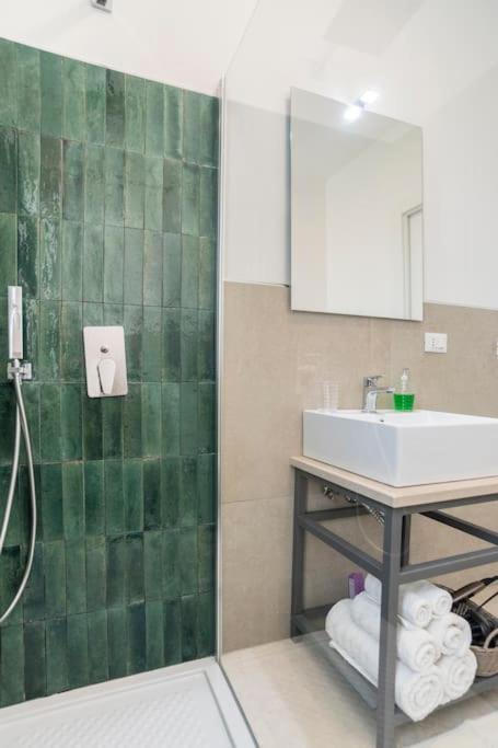 La salle de bains est pourvue d'un lavabo et d'un mur carrelé vert. dans l'établissement Le Perseidi Eco Home San Lorenzo, à Reitani 24 autres photos
