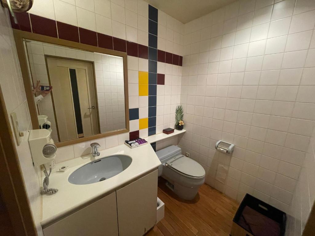 une salle de bain avec un lavabo, des toilettes et un miroir dans l'établissement Hotel Luxe - Adult Only, à Tokyo