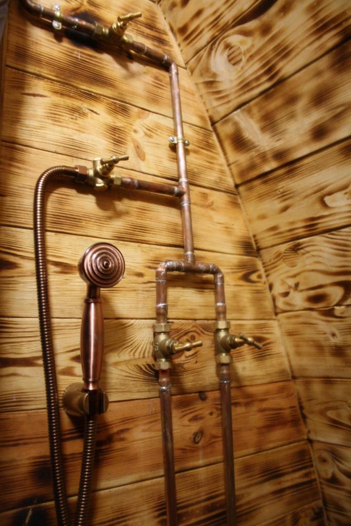 un mur en bois avec une douche et un tuyau dans l'établissement Lodges des Grands Chênes, à Andelarrot