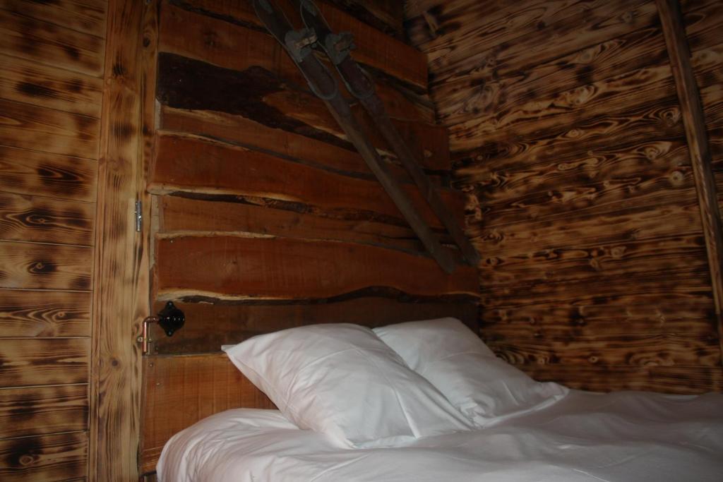 Ce lit se trouve dans une chambre en bois dotée d'oreillers blancs. dans l'établissement Lodges des Grands Chênes, à Andelarrot