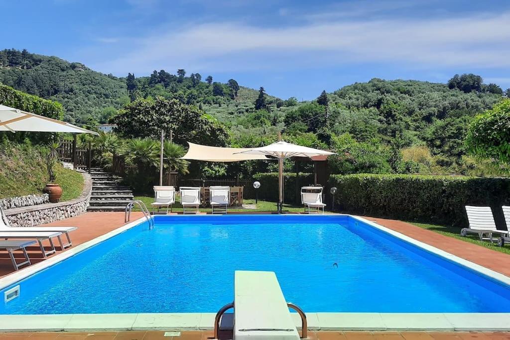 - une piscine bleue avec des chaises et un parasol dans l'établissement Veranda, a dream villa, with big private pool close to the beach, à Camaiore