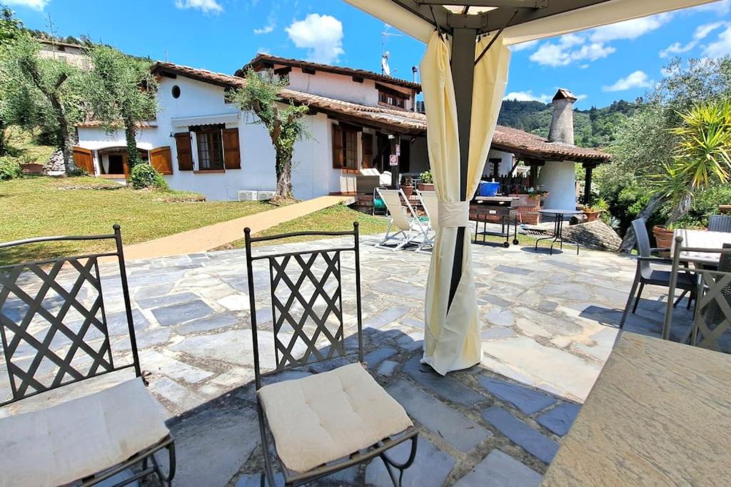 une terrasse avec 2 chaises et une maison dans l'établissement Veranda, a dream villa, with big private pool close to the beach, à Camaiore