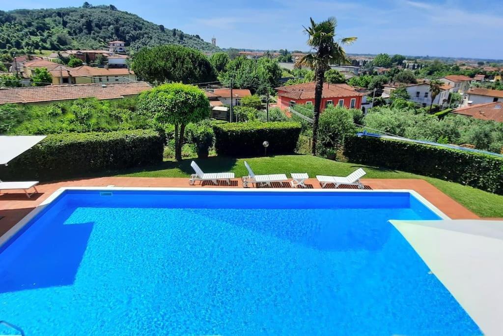 - une grande piscine bleue dans une cour avec des chaises dans l'établissement Veranda, a dream villa, with big private pool close to the beach, à Camaiore