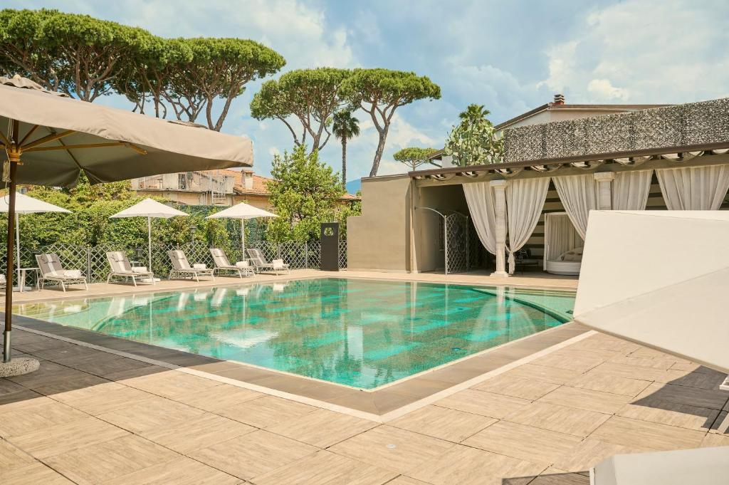 une piscine avec chaises et parasols dans un hôtel dans l'établissement Grand Hotel Imperiale, à Forte dei Marmi