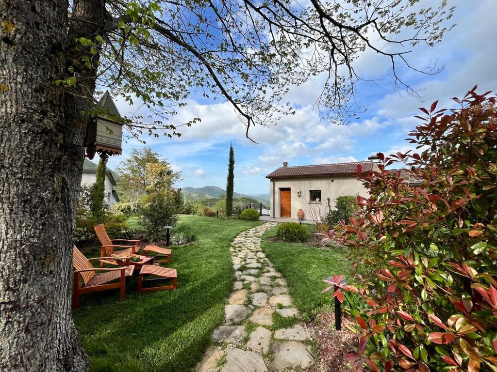 un jardin avec des bancs et un arbre ainsi qu'un bâtiment dans l'établissement Poggio Ancisa Relais, à Casteldelci