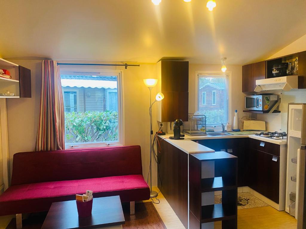 un salon avec un canapé rouge dans une cuisine dans l'établissement Mobilhome, à Azur
