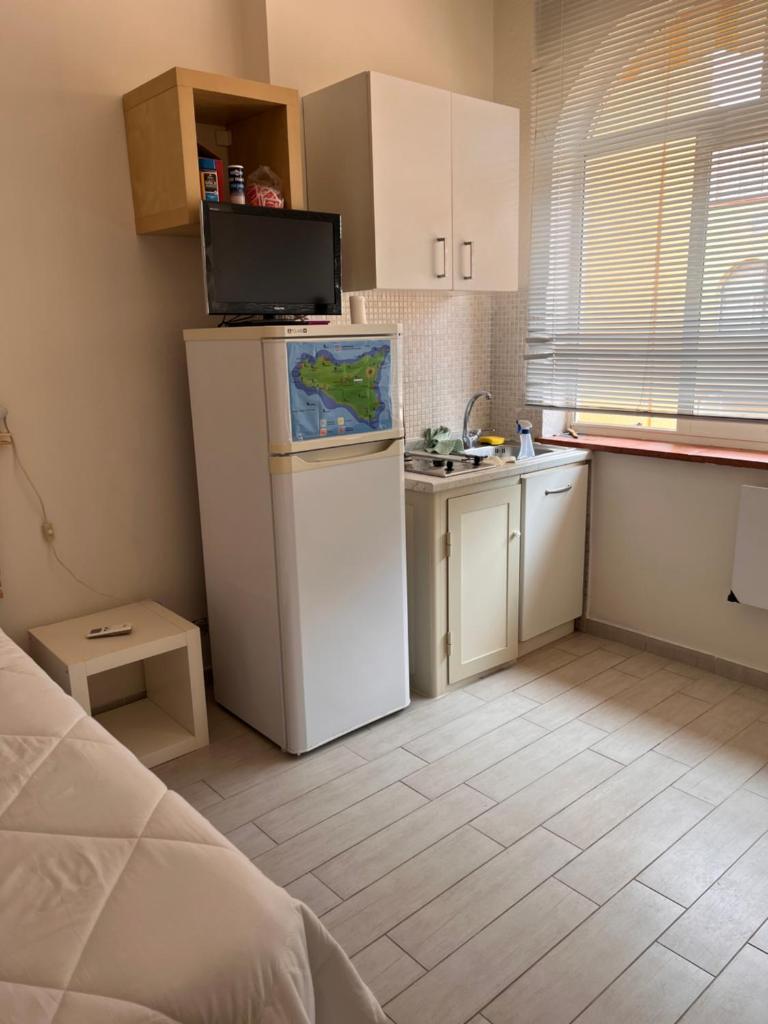 Elle comprend une petite cuisine équipée d'un réfrigérateur blanc et d'un évier. dans l'établissement Ashur mondello, à Palerme
