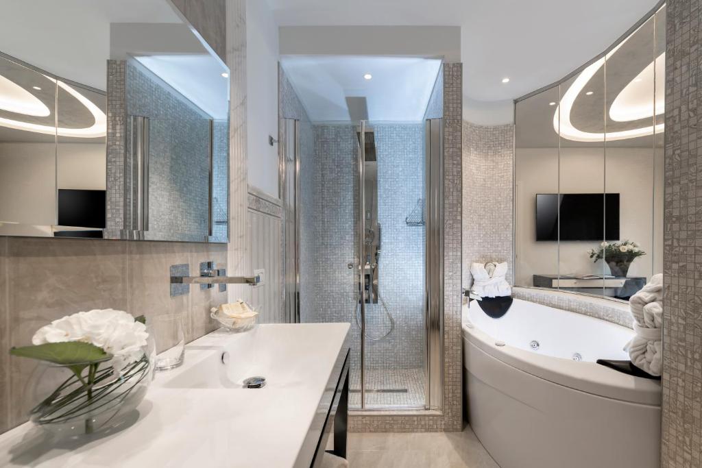 une salle de bain avec une baignoire, un lavabo et une douche dans l'établissement Grand Hotel Gallia, à Milano Marittima