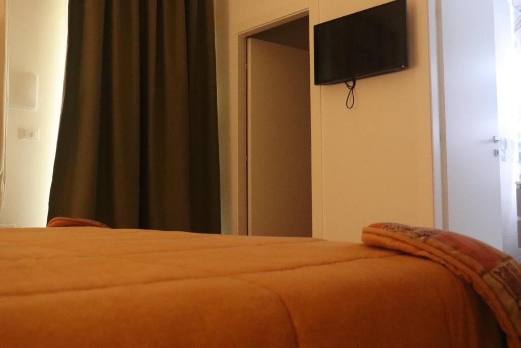 - une chambre avec un lit et une télévision murale dans l'établissement Da Nonno Pietro, à Pulsano