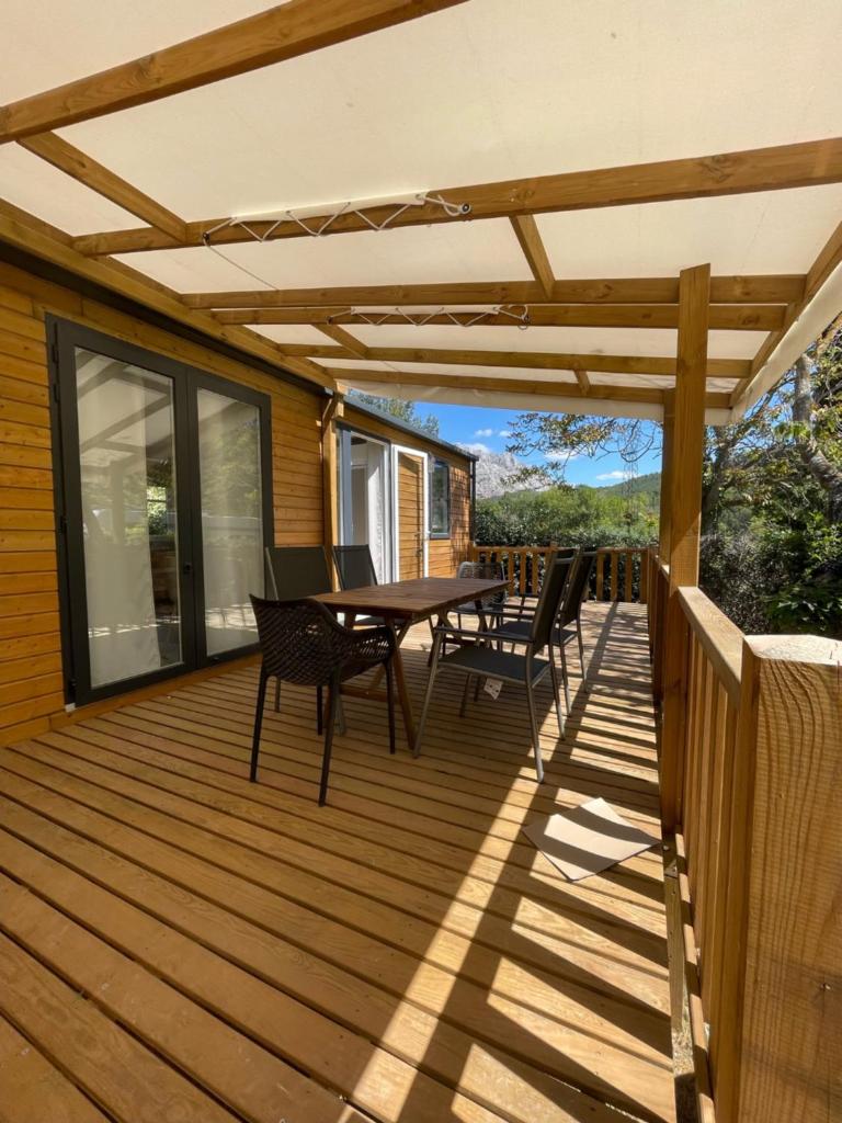 une terrasse en bois avec une table et des chaises dessus dans l'établissement Camping Sainte Victoire, à Beaurecueil