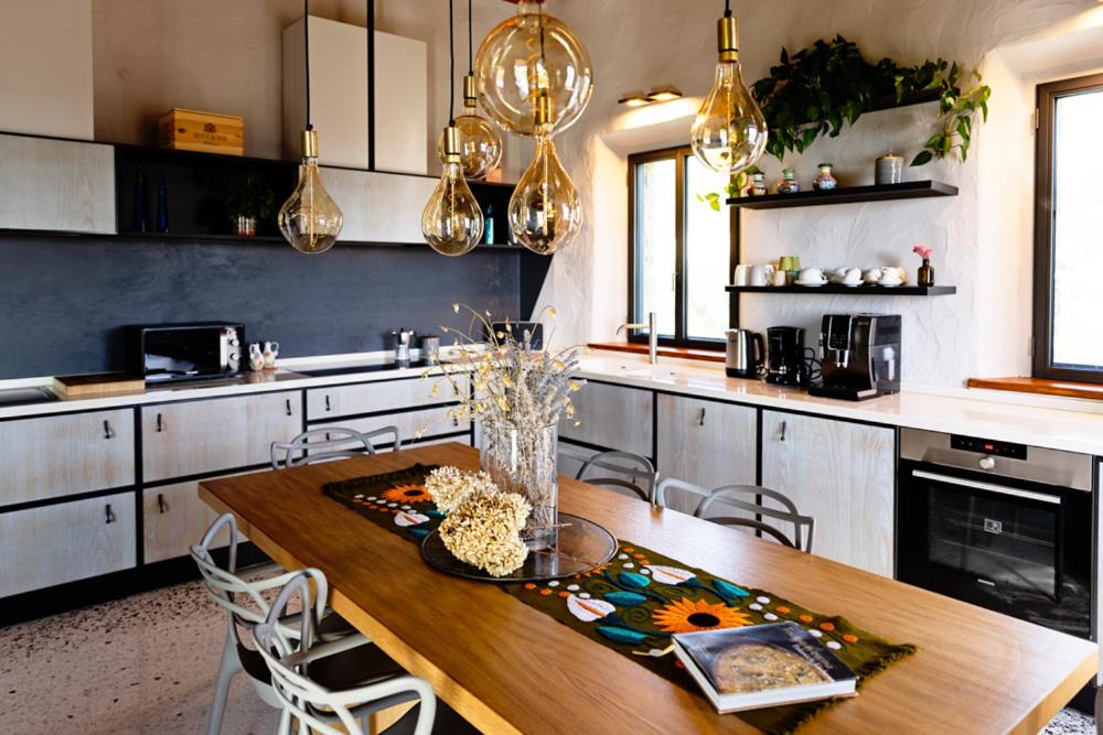 une cuisine avec une table en bois, des chaises et des lumières dans l'établissement Villa le Sughere - Privacy, Piscina e Vista Panoramica, à Castellina Marittima