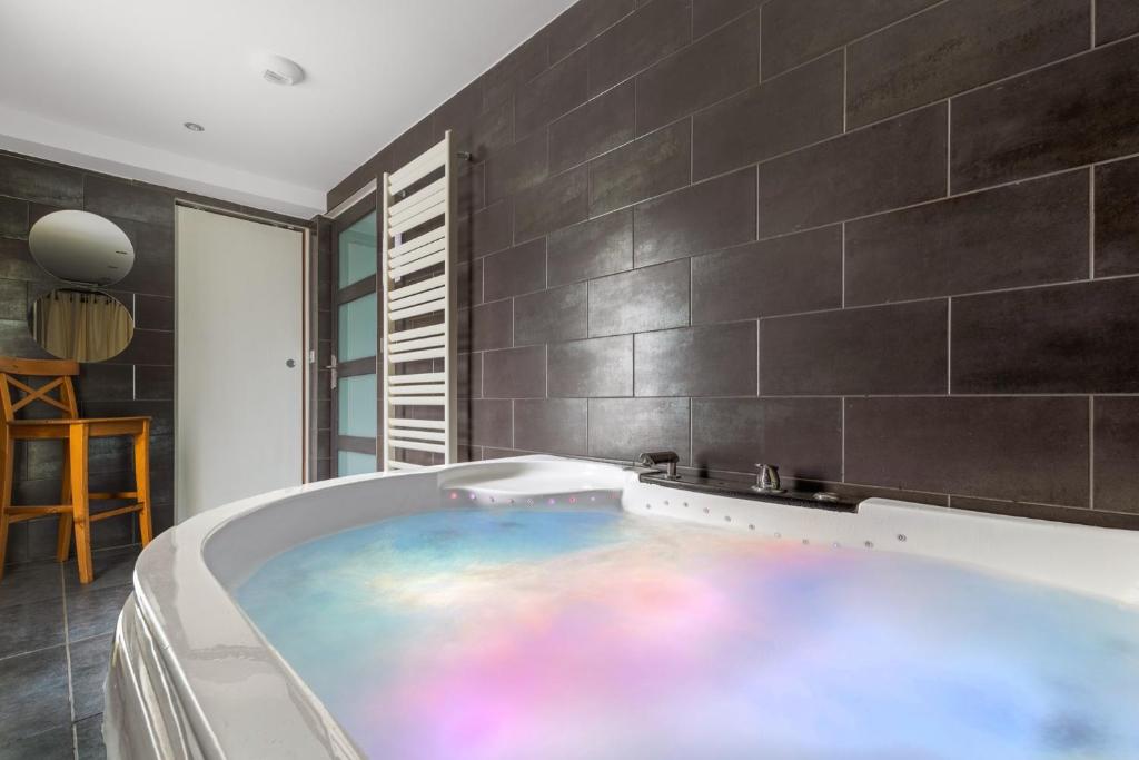 La salle de bains est pourvue d'un bain à remous et de carrelage noir. dans l'établissement Grand Chalet Standing Avec Jacuzzi à Chamrousse ski 1750, à Chamrousse