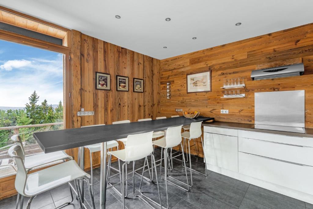 - une cuisine avec des murs en bois et un bar avec des tabourets dans l'établissement Grand Chalet Standing Avec Jacuzzi à Chamrousse ski 1750, à Chamrousse