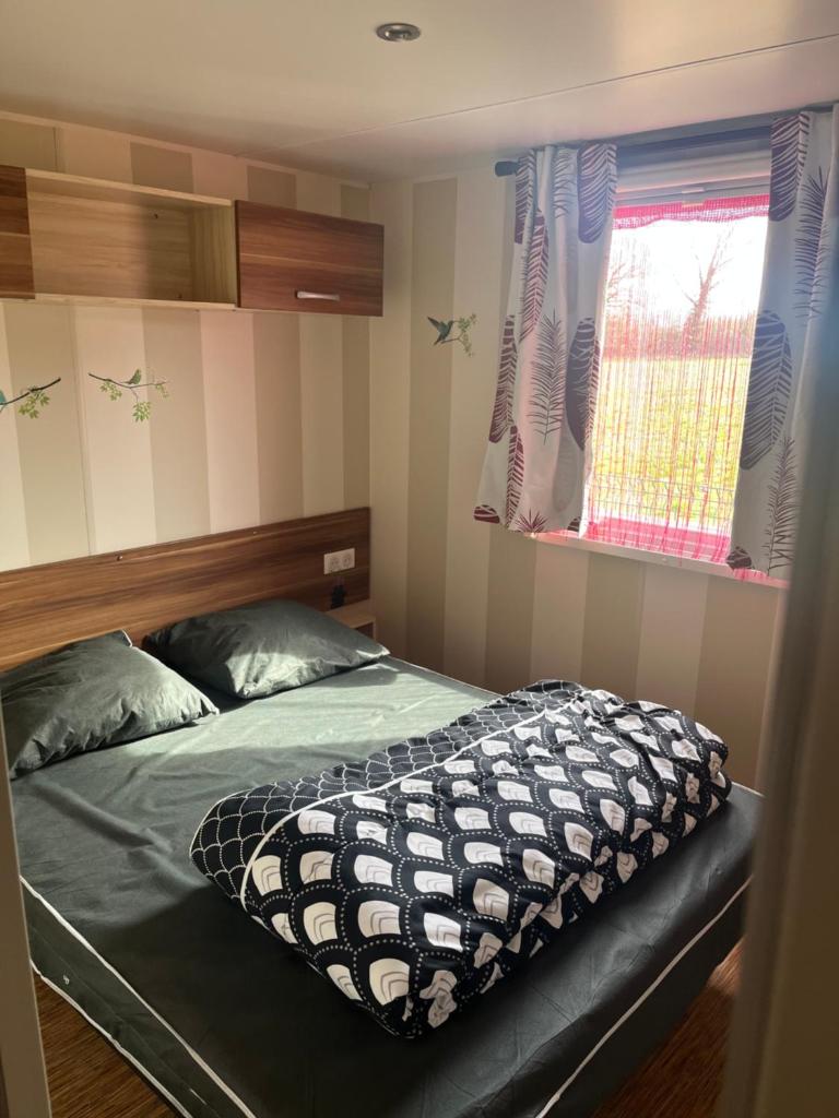 une chambre avec un lit et une fenêtre dans l'établissement Mobilhome camping proche des plages, à Saint-Jean-de-Monts