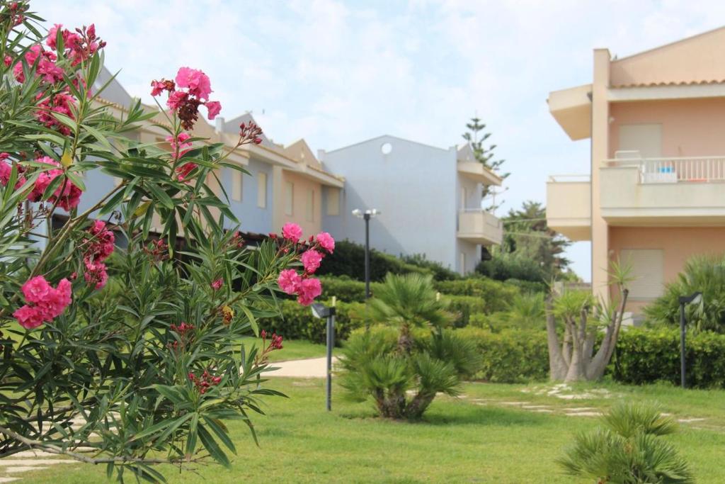 un jardin avec des fleurs roses devant un bâtiment dans l'établissement Agua Residence, à Noto
