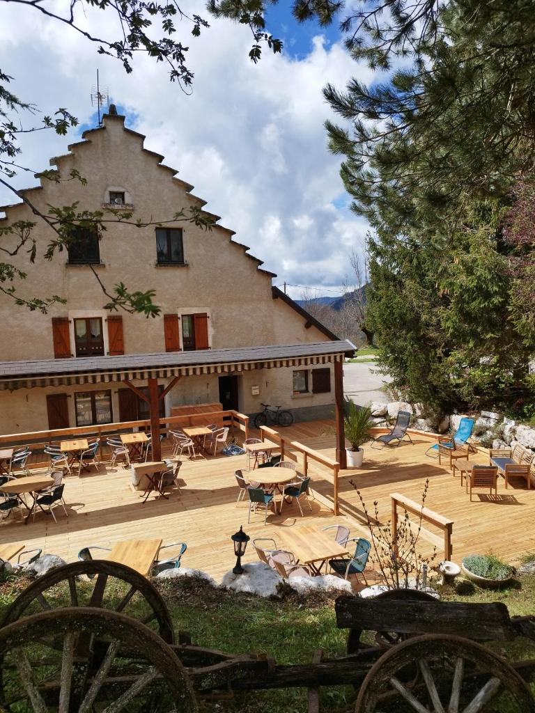 un grand bâtiment avec des tables et des chaises devant dans l'établissement Auberge des Montauds - Hôtel & Restaurant, à Villard-de-Lans