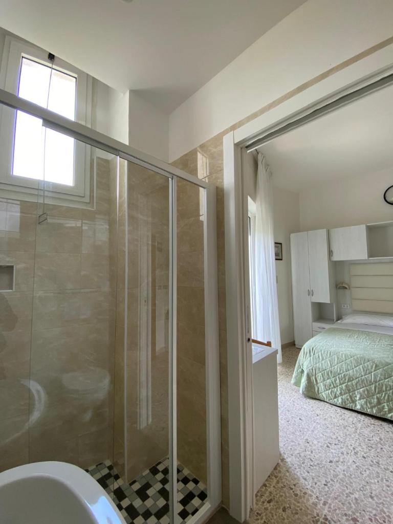 une salle de bain avec une douche en verre et un lit dans l'établissement Hotel Imperiale, à Cesenatico