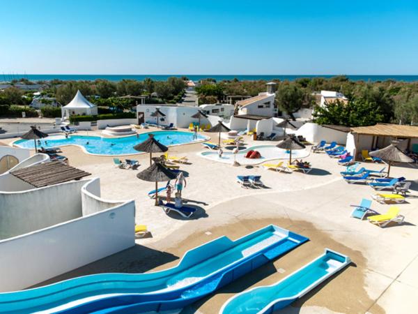une grande piscine avec chaises et parasols dans l'établissement Camping Le Clos du Rhône, à Saintes-Maries-de-la-Mer