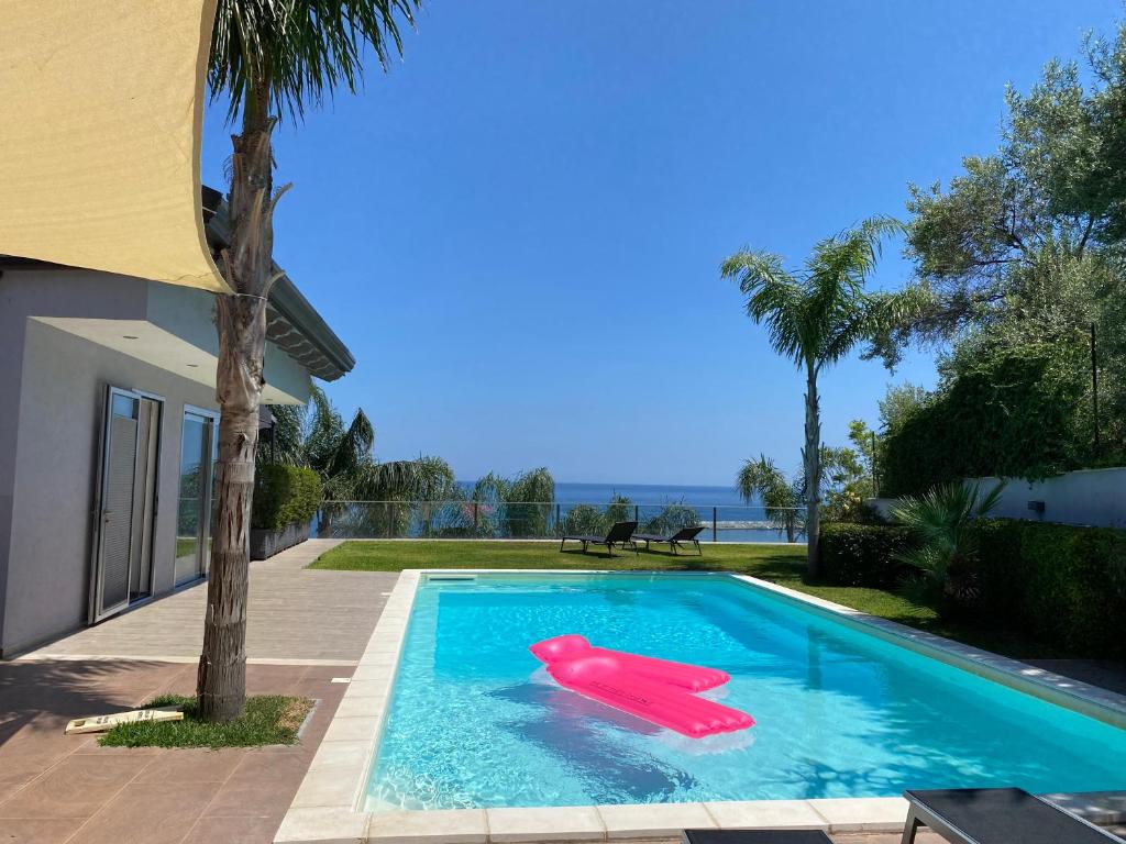 - une piscine avec un flottement rouge dans l'eau dans l'établissement LUXURY, VILLA VITTORIO, Pool, Taormina,Etna & Seaview, à Giardini Naxos