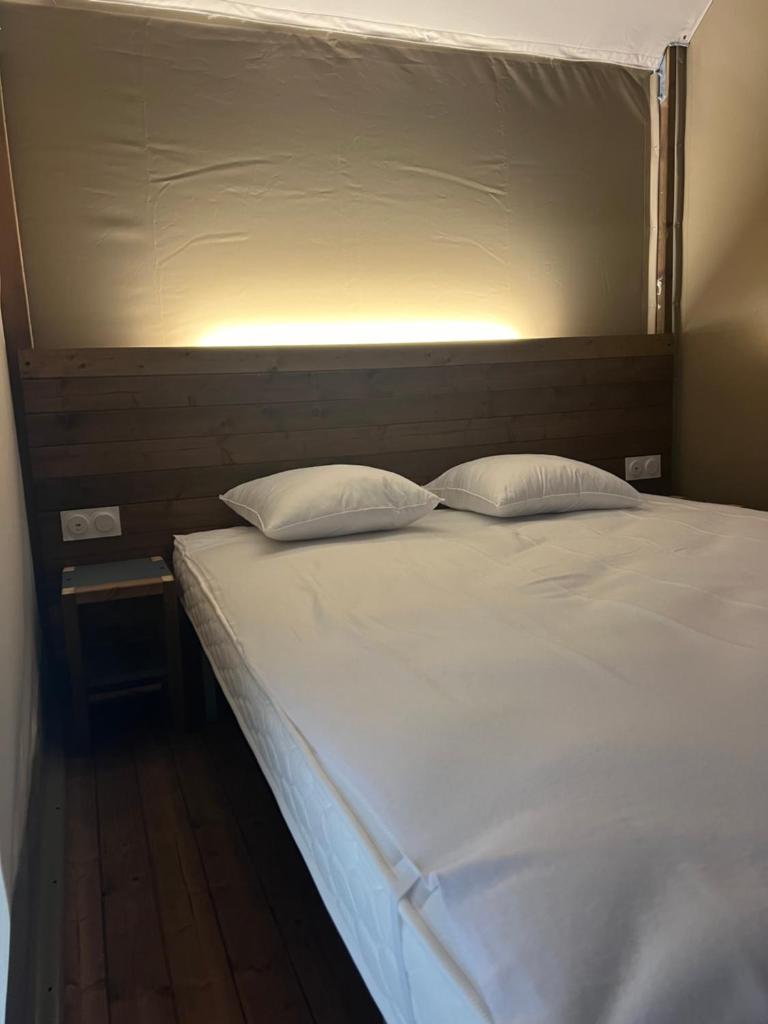 un lit blanc avec deux oreillers dessus dans l'établissement lodge lavallee, à Belvédère