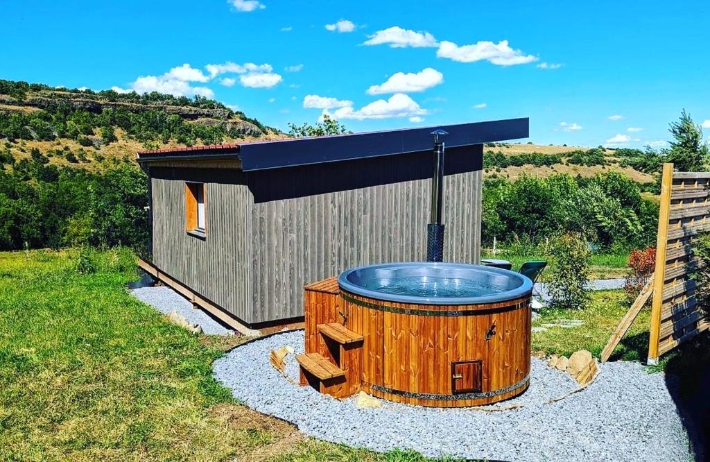 un bain à remous en face d'un petit bâtiment dans l'établissement Yourte ,volcans,randonnées,lacs,quiétude, à Grandeyrolles