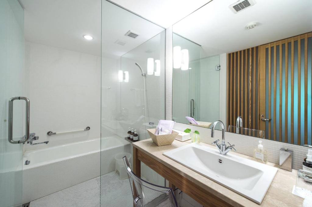 une salle de bain avec un lavabo, une baignoire et un miroir dans l'établissement Fujiiso, à Takayama