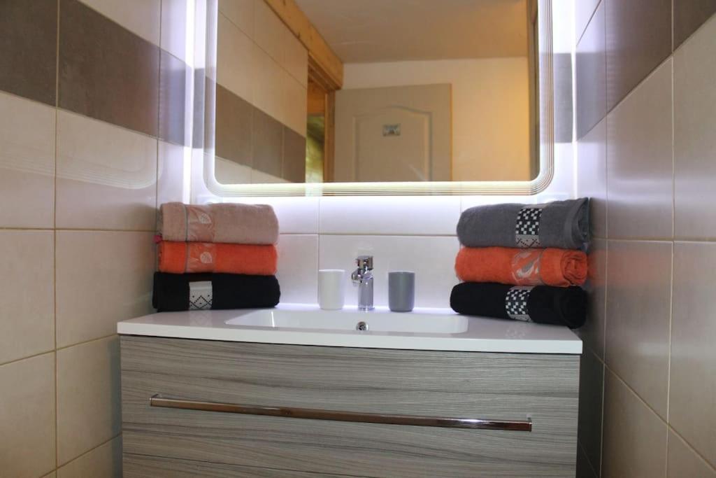 une salle de bain avec un lavabo avec un miroir et des serviettes dans l'établissement Spacieux T3 coeur de station, à Bernex 32 autres photos
