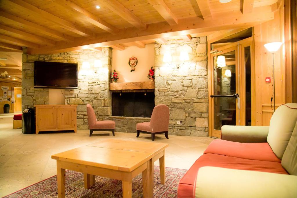 - un salon avec une cheminée en pierre, un canapé et des chaises dans l'établissement Les Alpages De Val Cenis, à Lanslebourg-Mont-Cenis