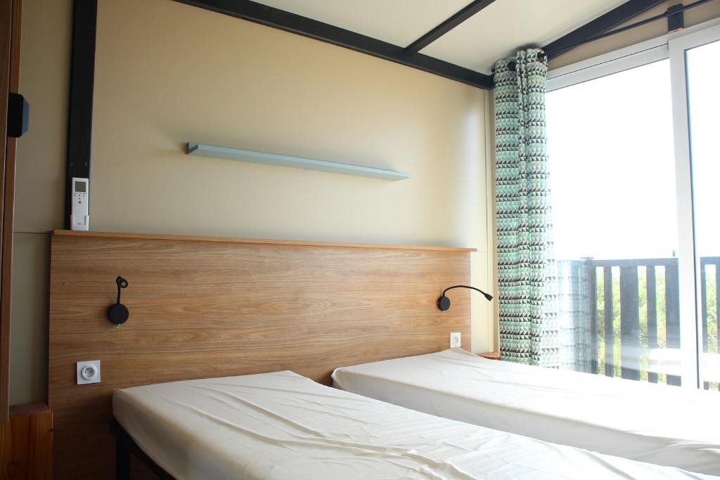 deux lits dans une chambre avec une grande fenêtre dans l'établissement Camping Le Clos du Rhône, à Saintes-Maries-de-la-Mer