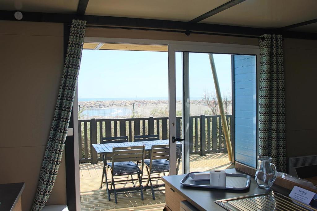 Il comprend une cuisine avec un balcon doté d'une table et de chaises. dans l'établissement Camping Le Clos du Rhône, à Saintes-Maries-de-la-Mer