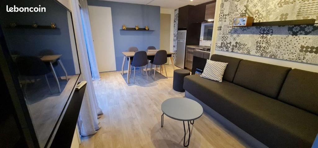 un salon avec un canapé, une table et des chaises dans l'établissement Bungalow Mobile Home de Luxe Vue Mer Saint-Raphaël 4 personnes, à Saint-Raphaël