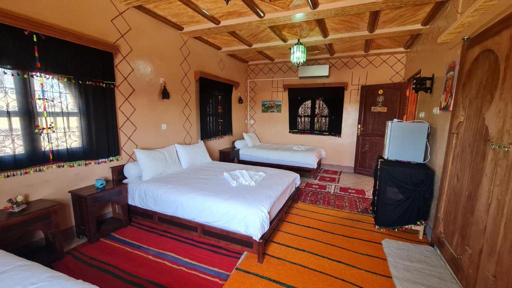 - une chambre avec 2 lits et une télévision dans l'établissement kasbah amlal, à Boumalne