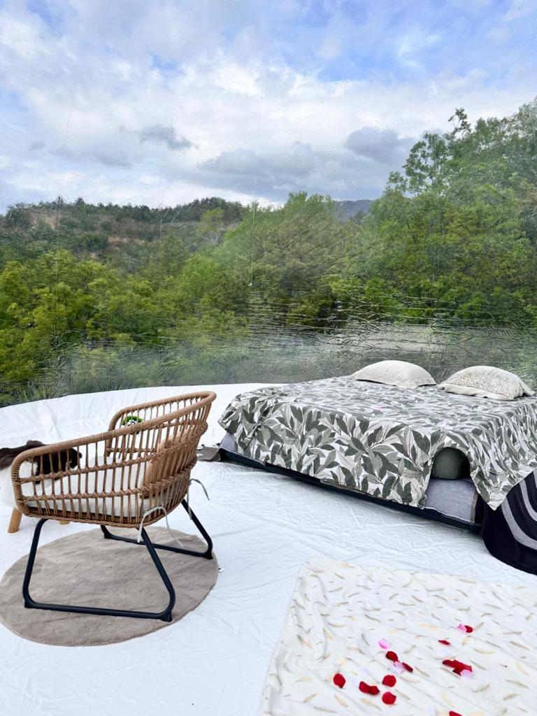 un lit et une chaise assis sur une terrasse dans l'établissement BULLE INSOLITE ATTRAPE REVE, à Thoard