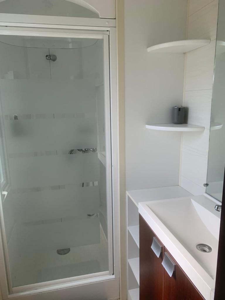 une salle de bain blanche avec une douche et un lavabo dans l'établissement Flo mobil home camping Poney trois étoiles route de Moustiers Ste Croix, à Sainte-Croix-de-Verdon 20 autres photos