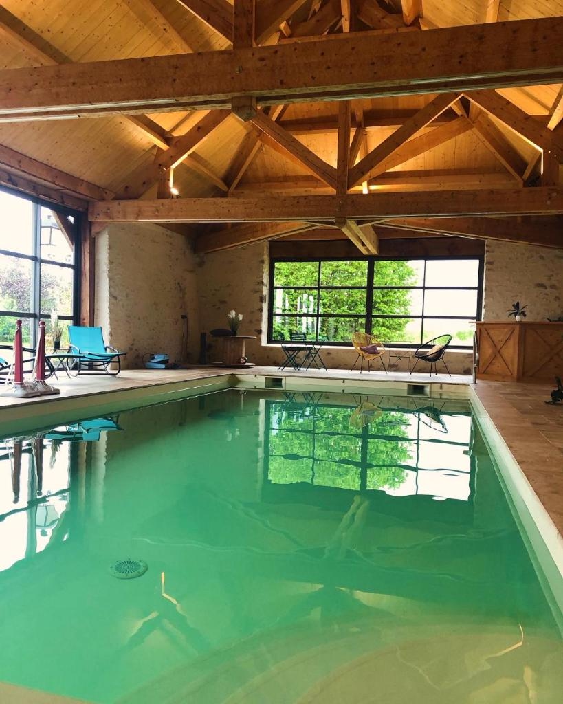 une piscine intérieure avec un plafond en bois et une grande salle dans l'établissement MAISON DE VACANCES AVEC PISCINE INTERIEURE - Le Grand Champagne, à Saint-Victeur