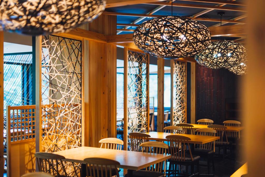une salle à manger avec tables, chaises et lustres dans l'établissement Tsuetate Onsen Hotel Hizenya, à Oguni