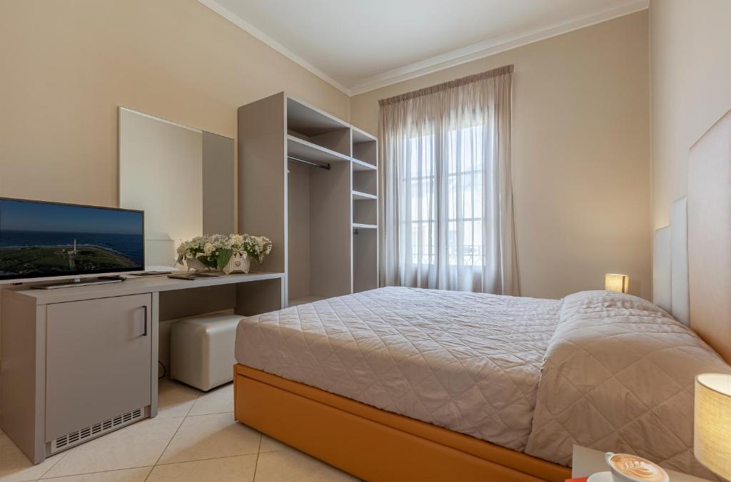 une chambre avec un lit et un bureau avec une télévision dans l'établissement Ghibli Hotel, à San Vito Lo Capo