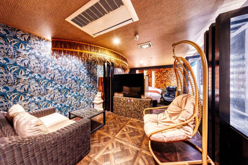 un salon avec un canapé, des chaises et une télévision dans l'établissement Hotel Lotus Ibaraki -Adult Only, à Fukui