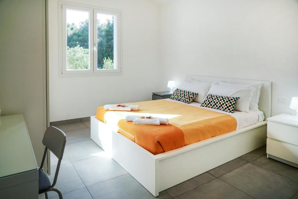 - une chambre blanche avec un lit et une couverture orange dans l'établissement Luxury Villa La Perla - Castellammare del golfo with Pool, Garden and Parking, à Castellammare del Golfo